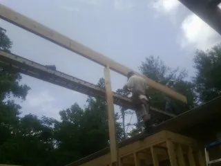 Carpenter setting a ridge beam over a new addition frame — Ice Dam Removal by Roofing Brothers in Ortonville