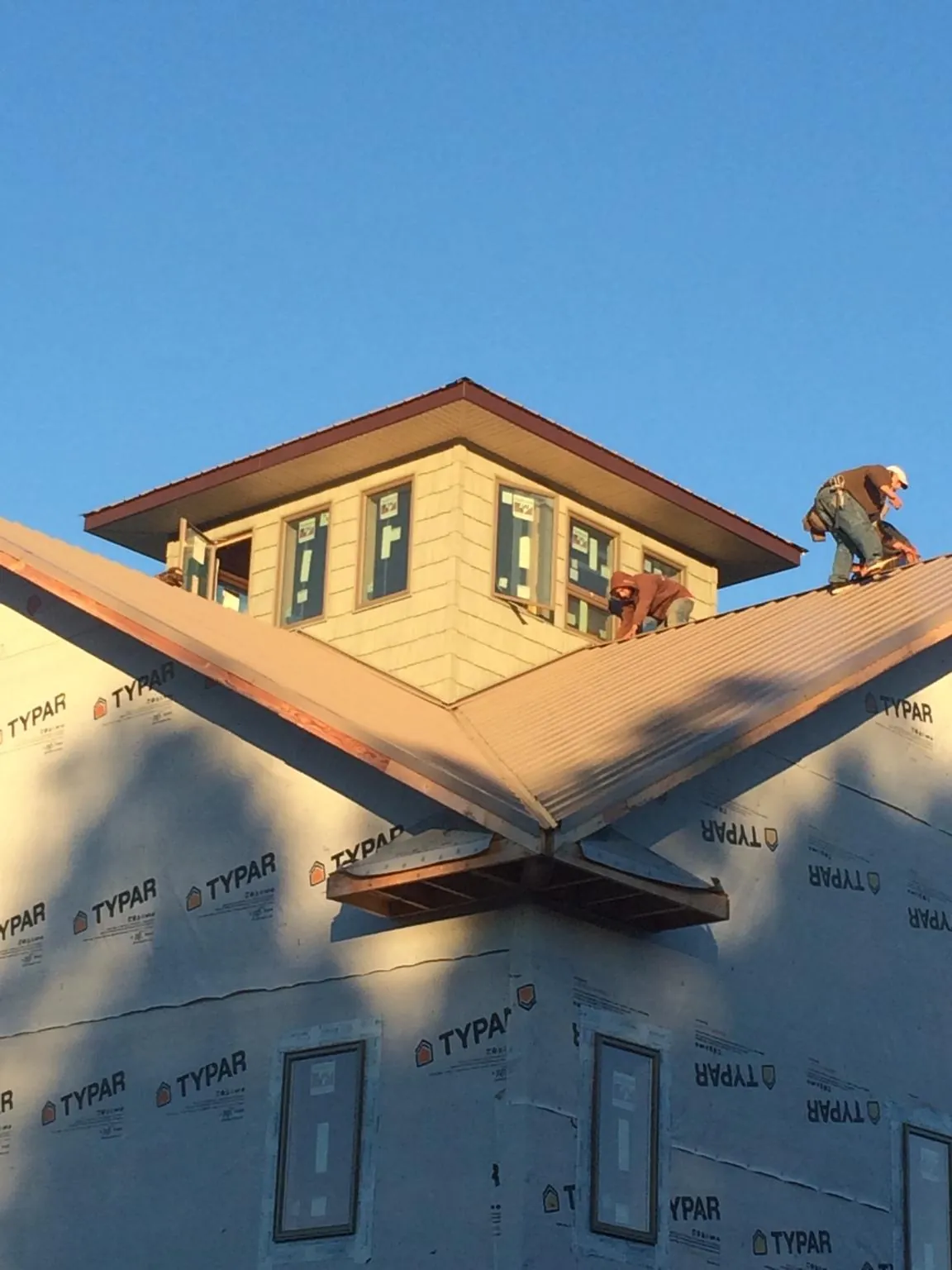 Roofers working around a rooftop cupola on a new metal roof at sunset — Roof Waterproofing in Ortonville by Roofing Brothers